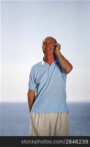 Senior man making telephone call by the coast