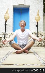 Senior Man Meditating Outdoors At Health Spa