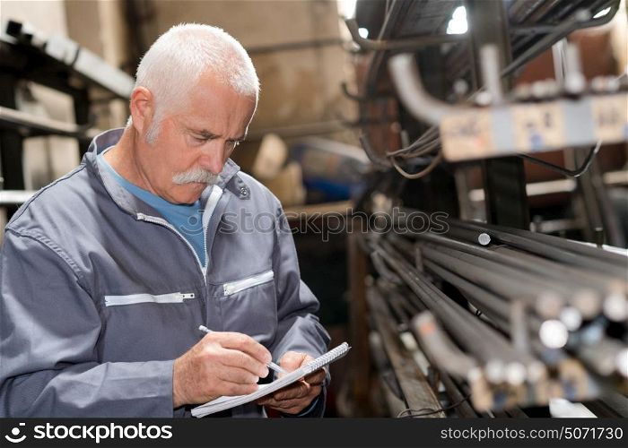 Senior man noting stock of metal rods