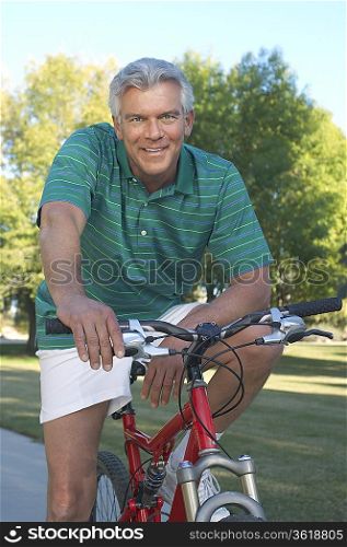 Senior man on bicycle in park, portrait