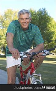 Senior man on bicycle in park, portrait