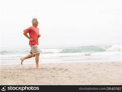 Senior Man On Holiday Running Along Winter Beach