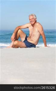 Senior Man On Holiday Sitting On Sandy Beach