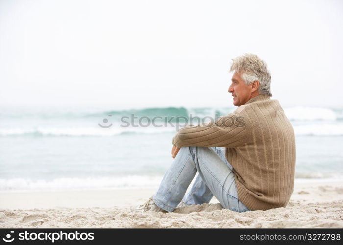 Senior Man On Holiday Sitting On Winter Beach