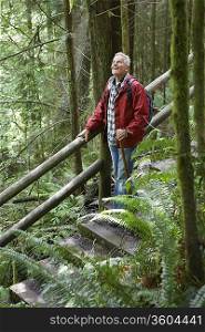 Senior man on trail in forest, looking up