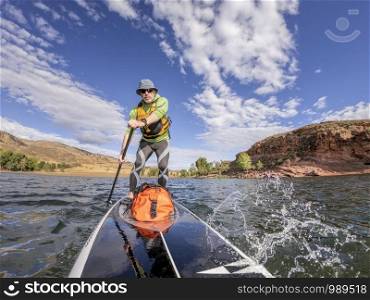 senior man paddling a stand up paddleboard against head wind on mountain lake - Horsetooth Reservoir , Colorado, in early fall scenery