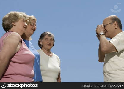 Senior man photographing three senior women