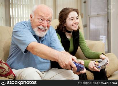 Senior man playing a video game with his teenage granddaughter.