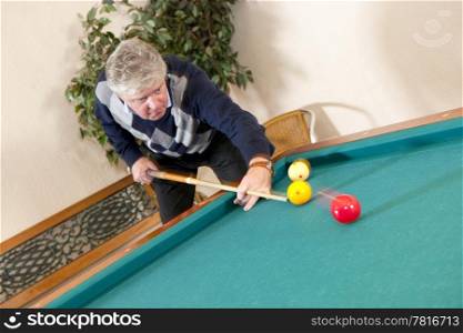 Senior man playing carambole billiards