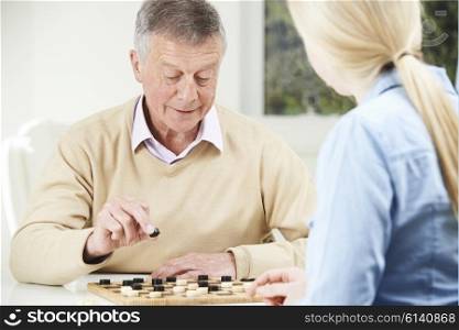 Senior Man Playing Checkers With Teenage Daughter