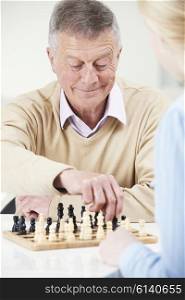 Senior Man Playing Chess With Teenage Granddaughter