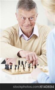 Senior Man Playing Chess With Teenage Granddaughter