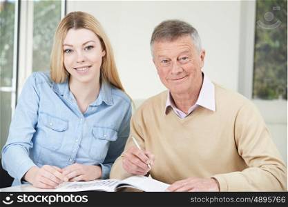Senior Man Playing Completing Crossword Puzzle With Teenage Granddaughter