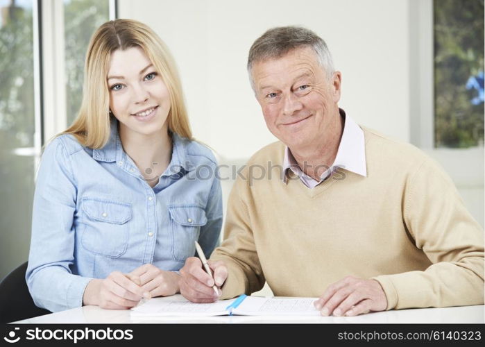 Senior Man Playing Completing Sudoku Number Puzzle With Teenage Granddaughter