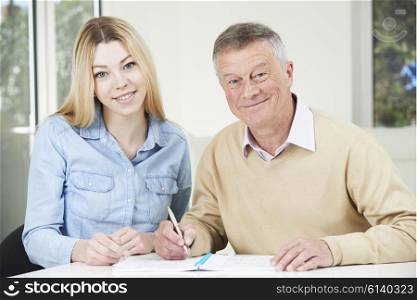 Senior Man Playing Completing Sudoku Number Puzzle With Teenage Granddaughter