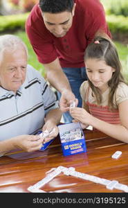 Senior man playing domino with his granddaughter and son