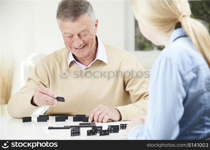 Senior Man Playing Dominoes With Teenage Granddaughter