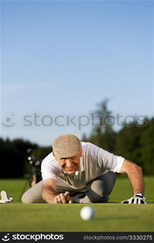 Senior man playing golf aiming for the hole, it is a wonderful clear summer late afternoon, the colors are very vivid