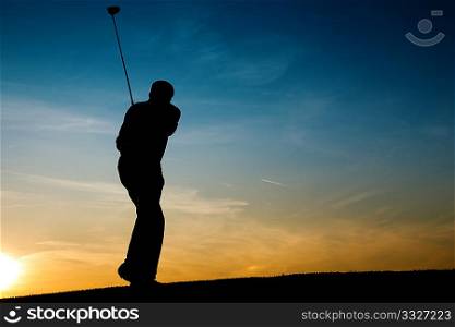 Senior man playing golf - pictured as a silhouette against an evening sky