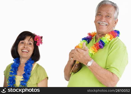 Senior man playing ukulele with a senior woman dancing beside him