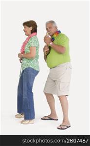 Senior man playing ukulele with a senior woman dancing in front of him