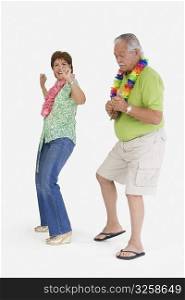 Senior man playing ukulele with a senior woman dancing in front of him