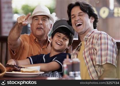 Senior man pointing forward with his son and grandson smiling