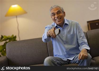 Senior man pointing while watching television at home