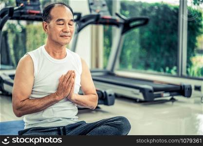 Senior man practice yoga in fitness gym. Mature healthy lifestyle.