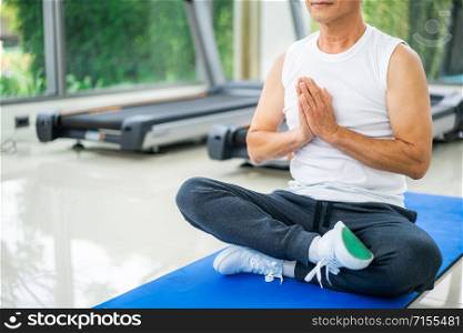 Senior man practice yoga in fitness gym. Mature healthy lifestyle.