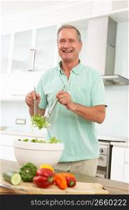 Senior Man Preparing Salad In Modern Kitchen