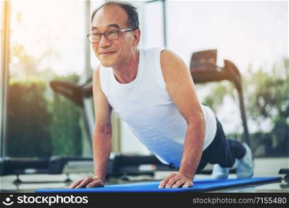 Senior man push up in fitness gym. Mature healthy lifestyle.