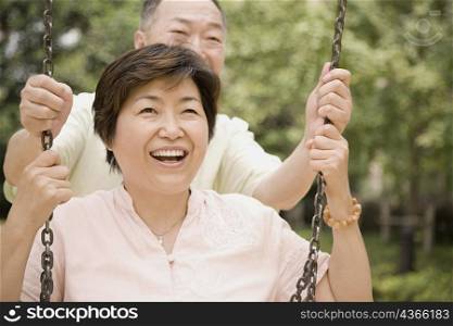 Senior man pushing a mature woman on a swing