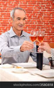 Senior man raising a glass in a restaurant