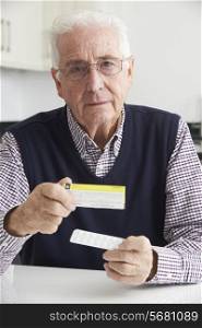 Senior Man Reading Information On Drug Packaging