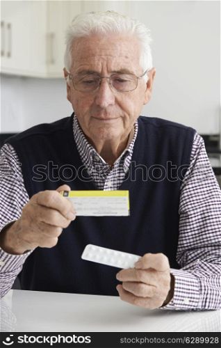 Senior Man Reading Information On Drug Packaging