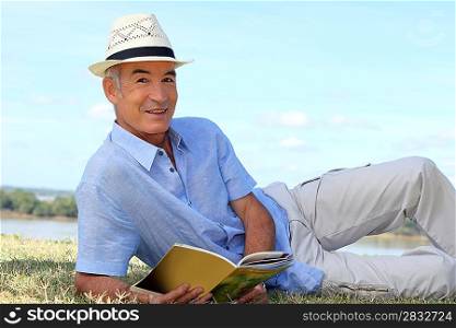 Senior man reading on the grass