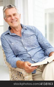 Senior man relaxing at home with a book