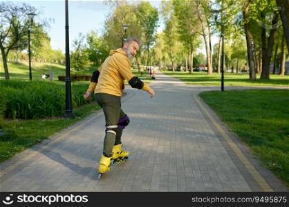 Senior man riding roller skates looking back at camera. Healthy lifestyle and rollerblading concept. Senior man riding roller skates looking back at camera
