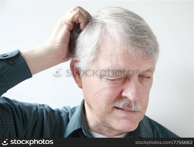 Senior man scratches his itchy scalp.