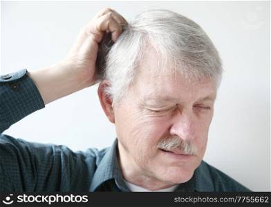 Senior man scratches his itchy scalp.