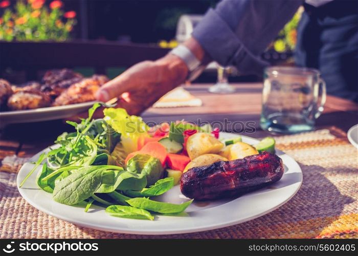 Senior man serving salad and meat at barbecue