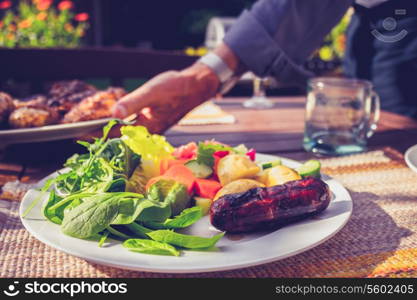 Senior man serving salad and meat at barbecue