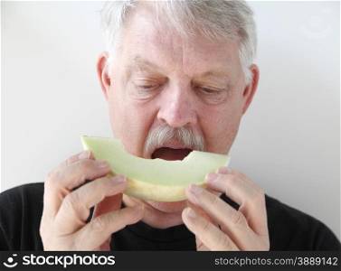 senior man set to bite into fresh fruit