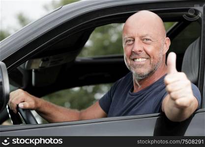senior man showing ok in car