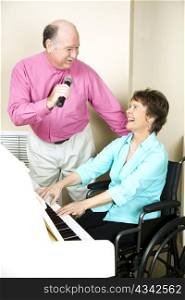 Senior man sings to a pianist in a wheelchair.