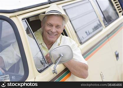 Senior man sits in drivers seat of campervan leaning through window