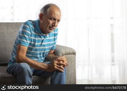 Senior man sitting at home with a knee pain.  Health and fitness   
