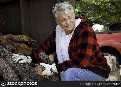 Senior man sitting besides firewood log