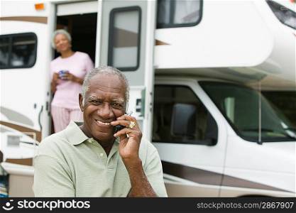 Senior man sitting in front of a caravan